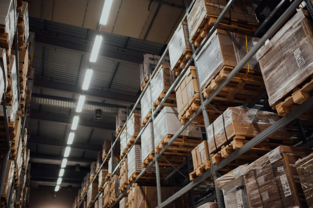 A large, modern warehouse with high ceilings and rows of shelving units stocked with goods.